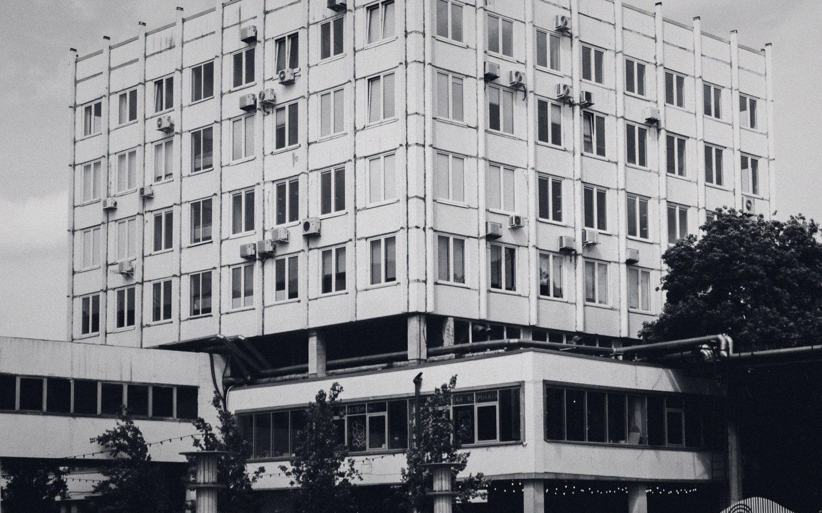 Multi-story concrete apartment block with rows of air conditioning units on its facade