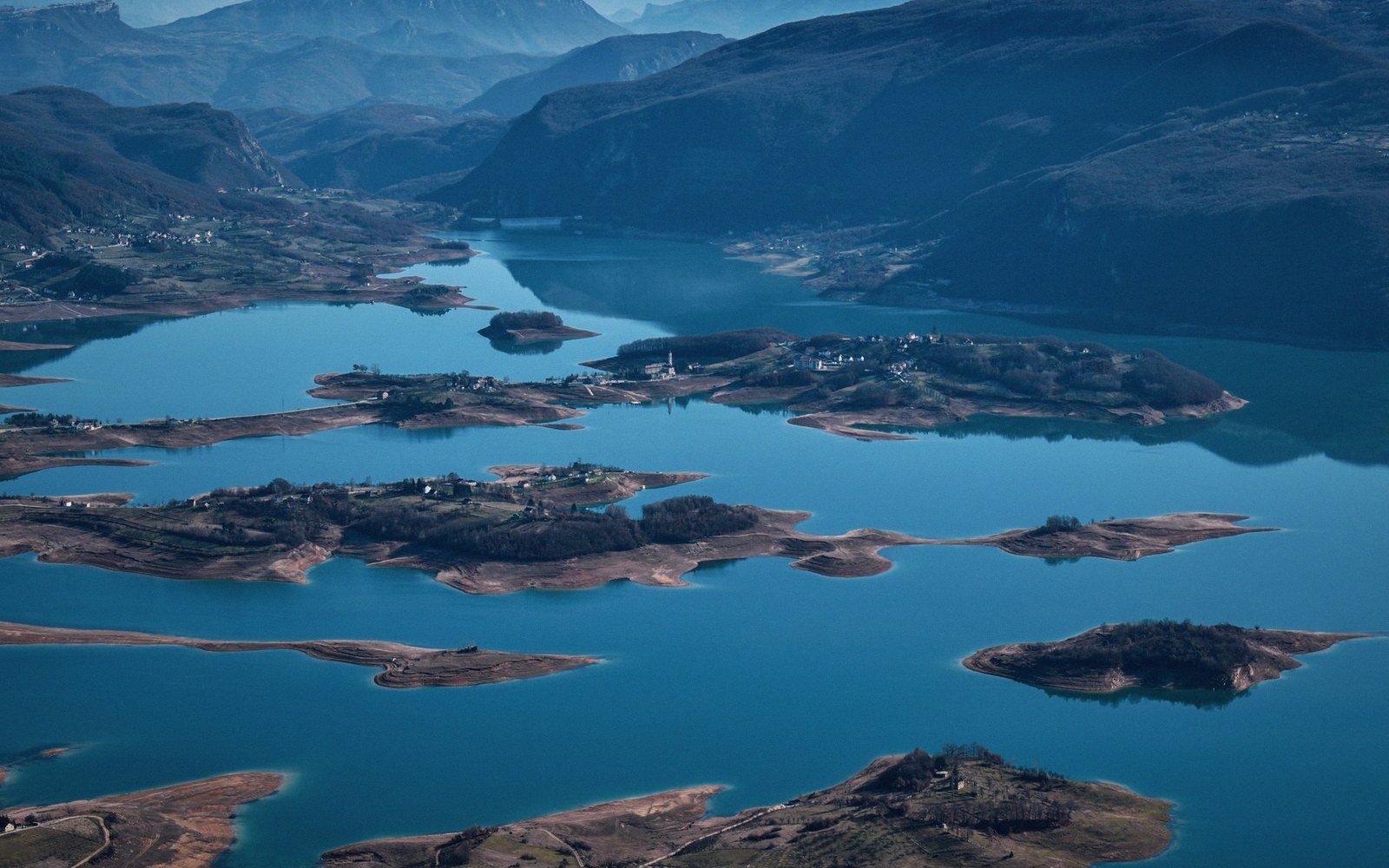 Aerial view of a mountain reservoir with scattered islands and low peninsulas of exposed land
