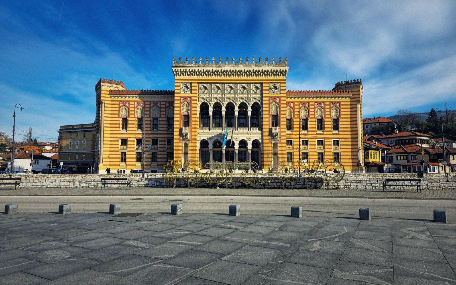 Striped yellow and red facade of Sarajevo's city hall under a blue sky